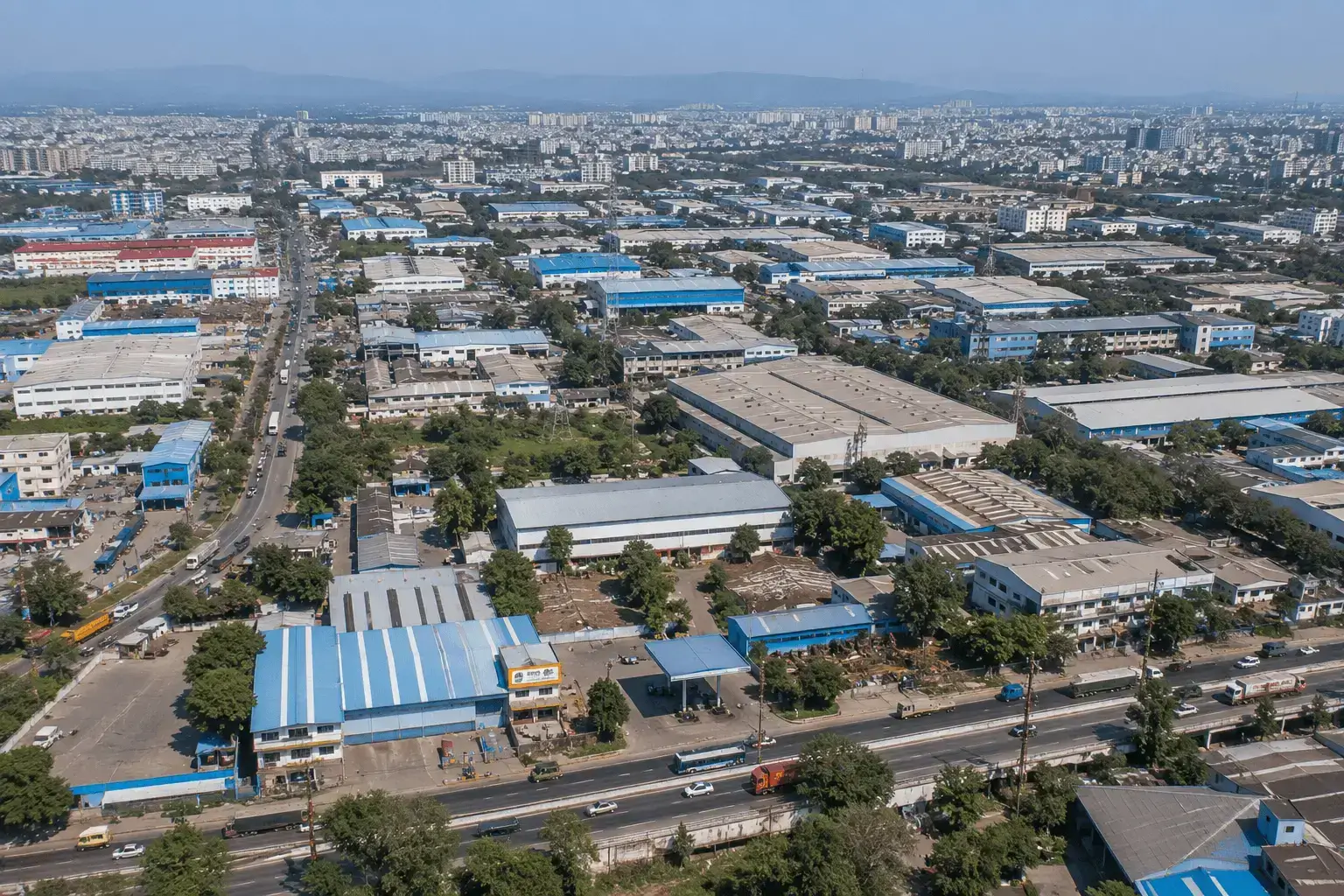 Aerial view of manufacturing plants, industrial sheds, and arterial roadways within the Bhosari MIDC industrial zone.