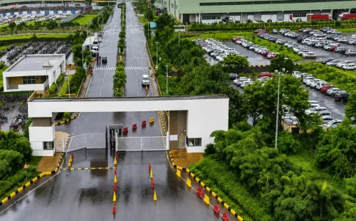 Aerial view of a gated factory entrance and modern manufacturing facilities in the Chakan Industrial Area.